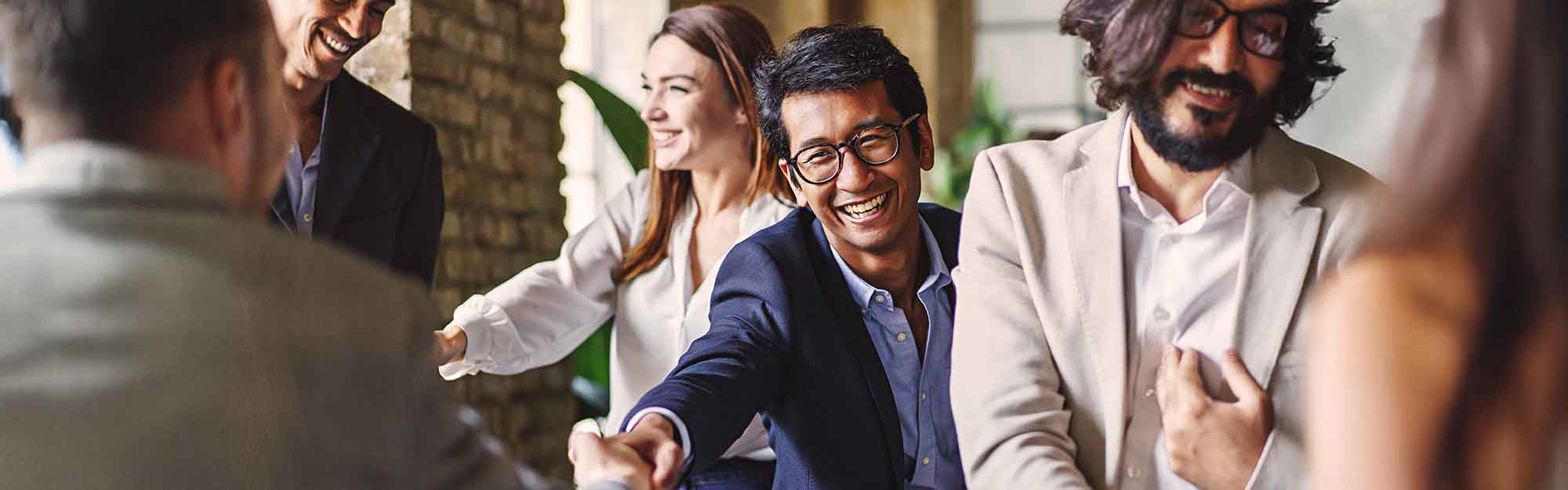 Group of diverse professionals celebrating with a handshake at a corporate event, embodying teamwork and achievement.